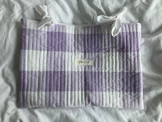 Quilted laptop sleeve with purple and white checkered pattern on a light gray background